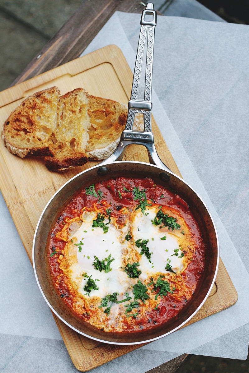 Shakshuka with eggs, tomatoes and herbs in a pan